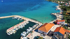 A coastal town with a marina, clear waters, and buildings with red-tiled roofs. - House Sea Stone (Pasman)