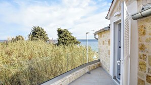 A balcony with a stone wall, a door, and a view of the sea. - House Sea Stone (Pasman)