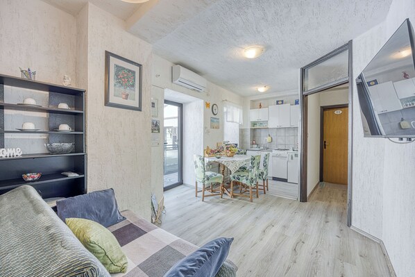 Ett kompakt bostadsutrymme med en soffa, ett matbord och ett litet kök.
