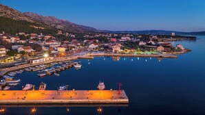 A coastal town with a marina, houses, and a mountain backdrop. - Apartments and Room Adriana (Starigrad)