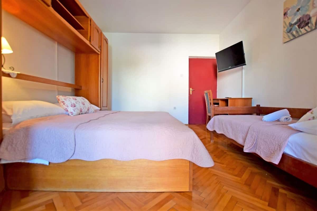 A bedroom with two beds, wooden furniture, a TV, and a red door.