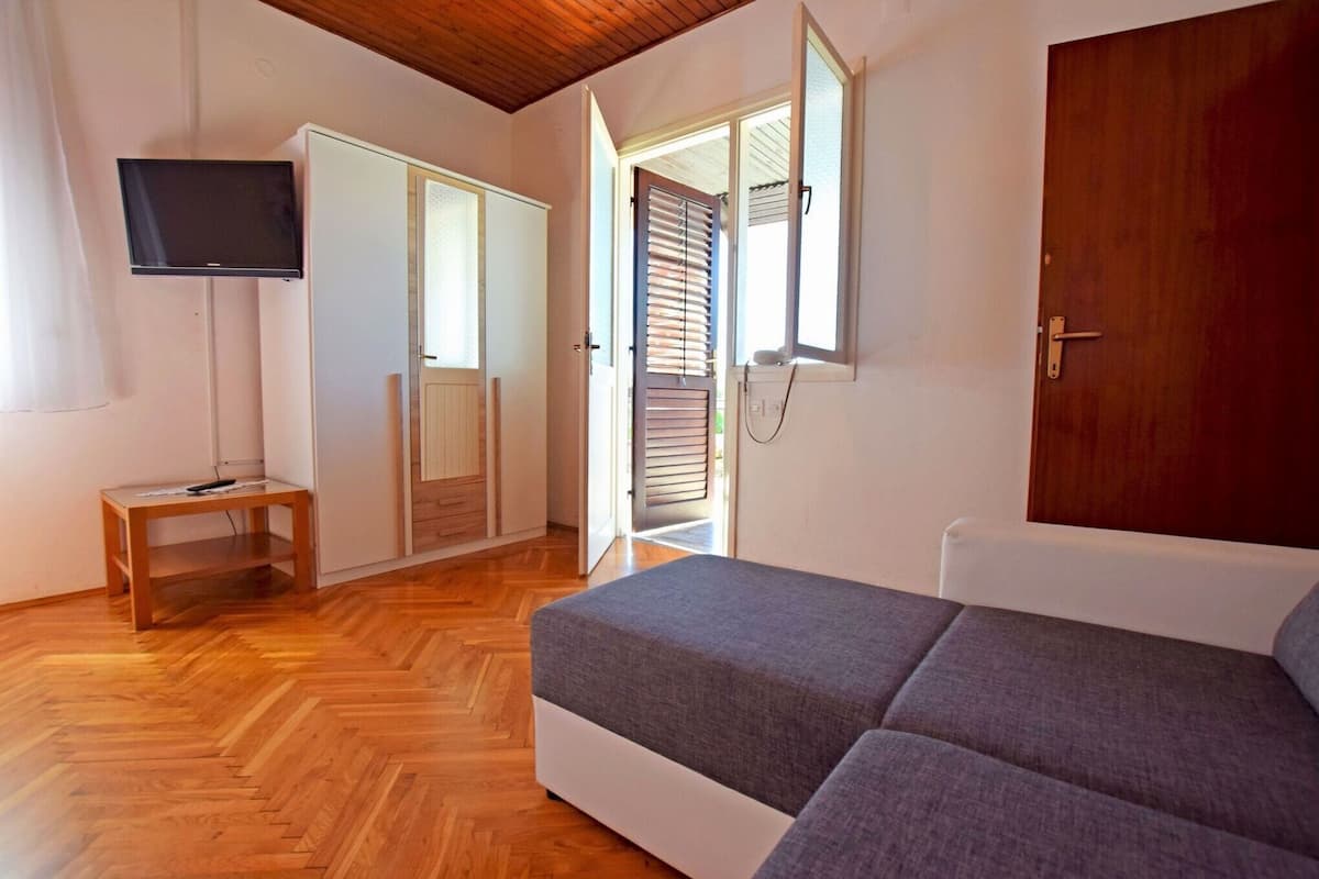 A bedroom with a bed, a television, a wooden table, and a wardrobe.