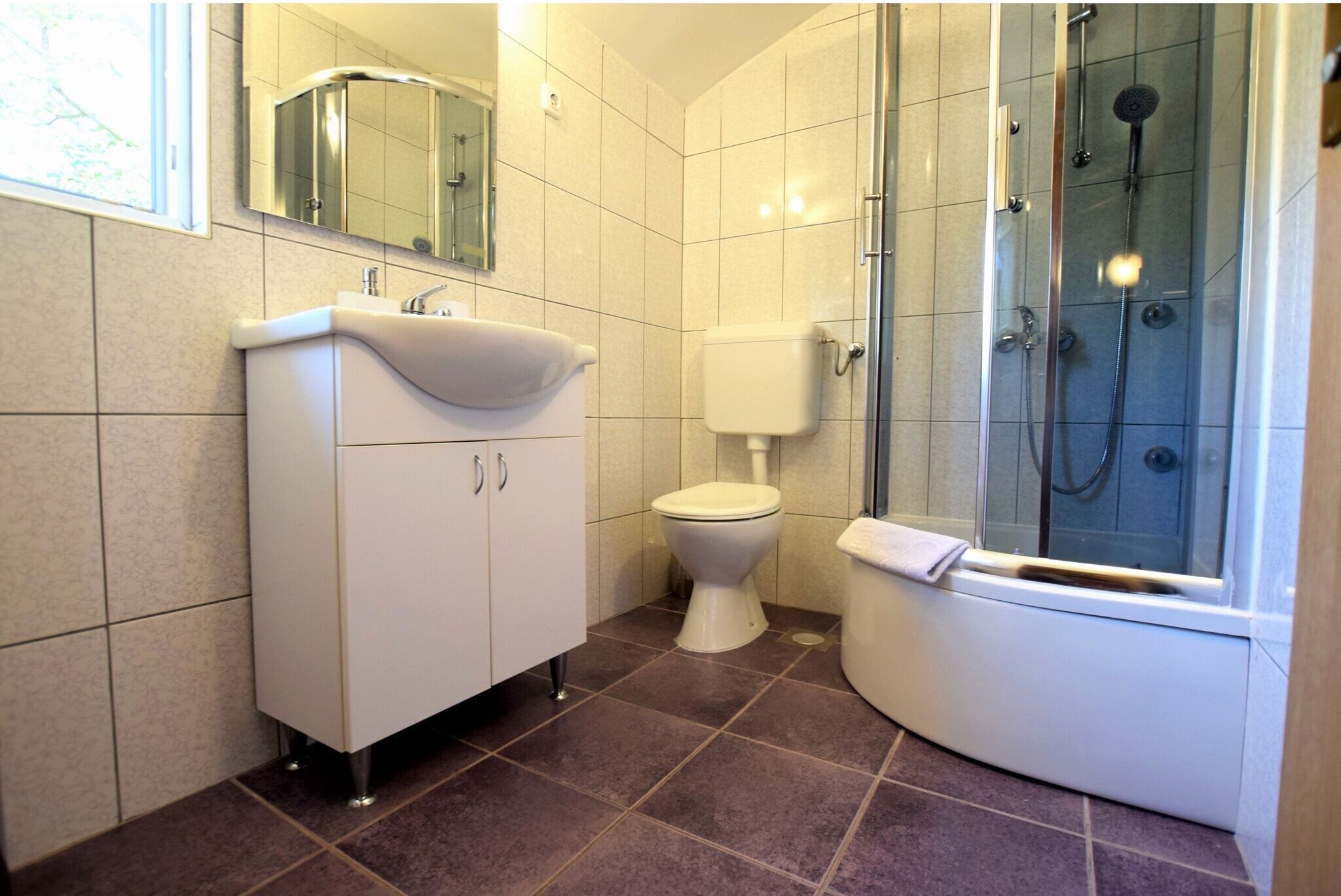 A bathroom with a white sink, toilet, and glass-enclosed shower.