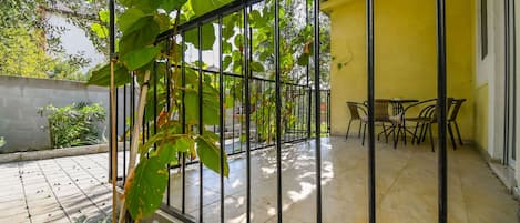 A covered patio with a tiled floor, a metal railing, and a table with chairs.