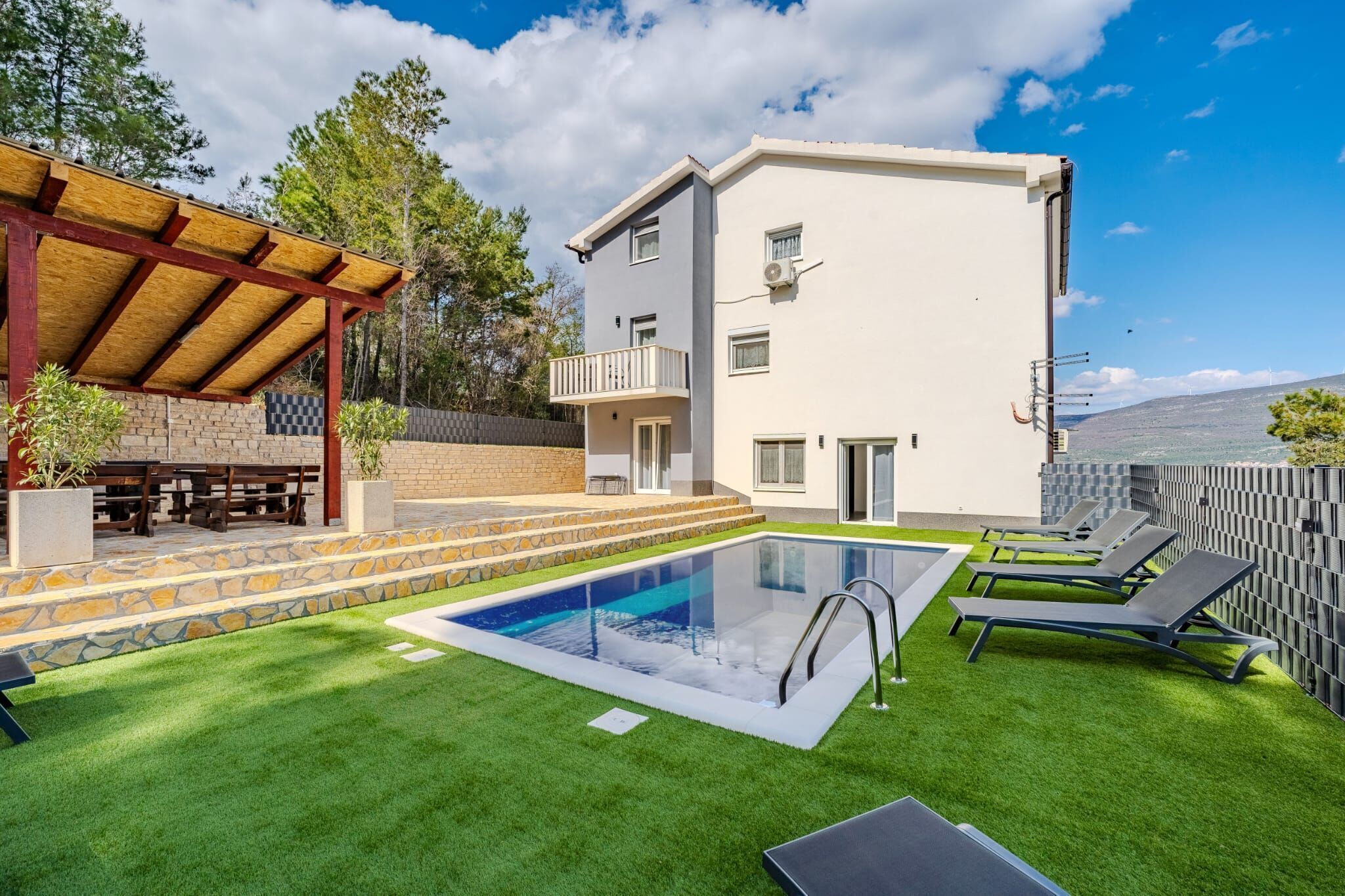 A modern building with a pool, outdoor seating, and a view of the landscape.