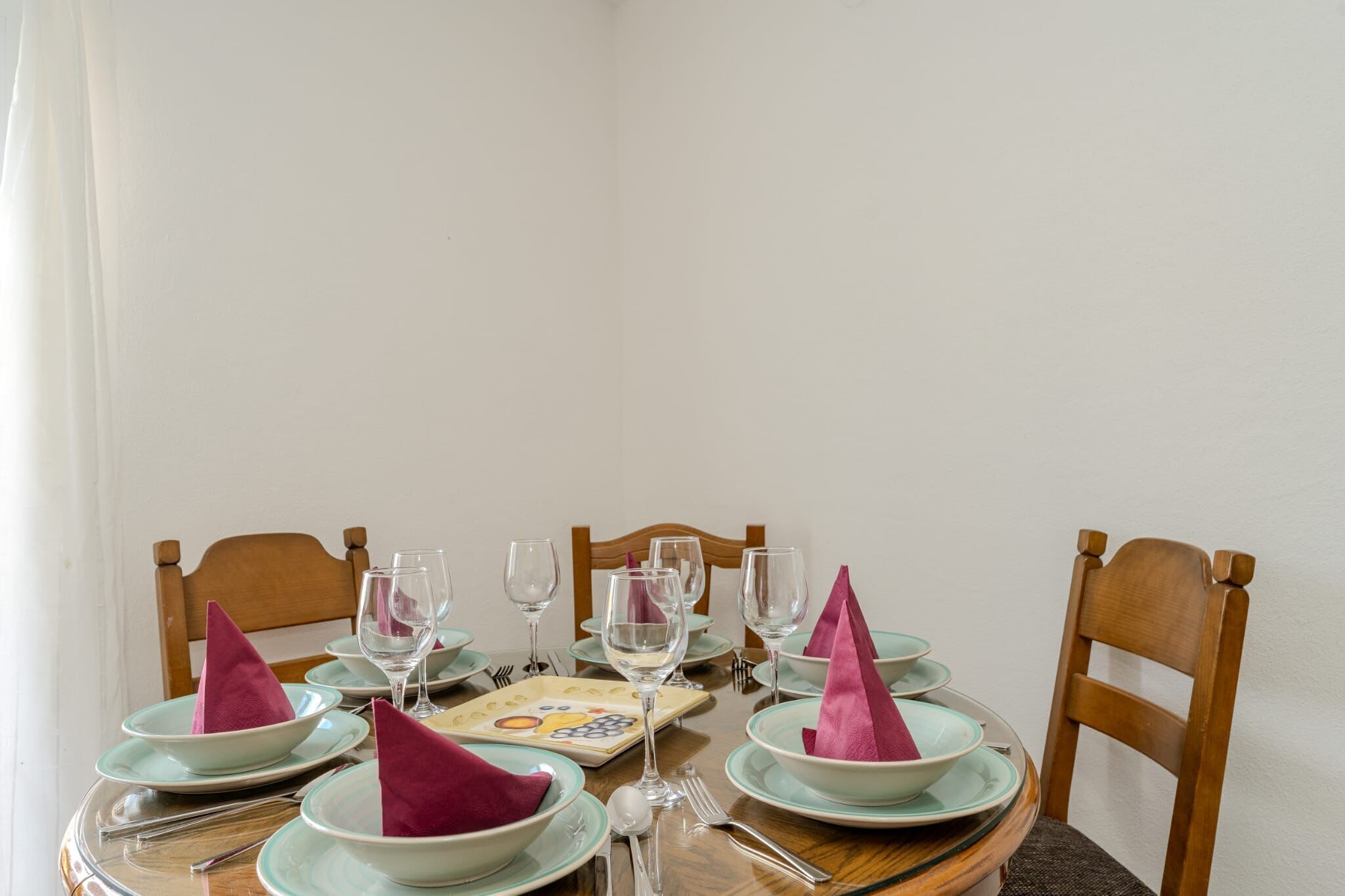 Une table à manger dressée avec des assiettes, des verres et des serviettes.