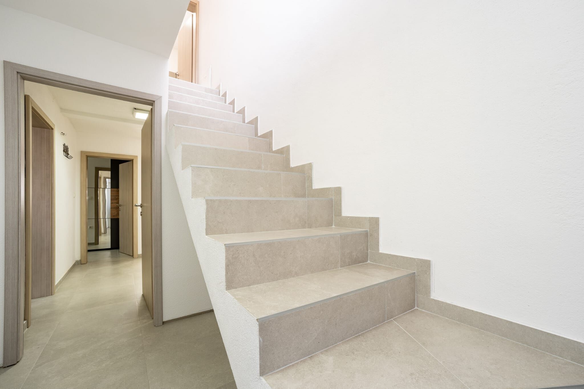 A staircase with beige steps leading to a landing.