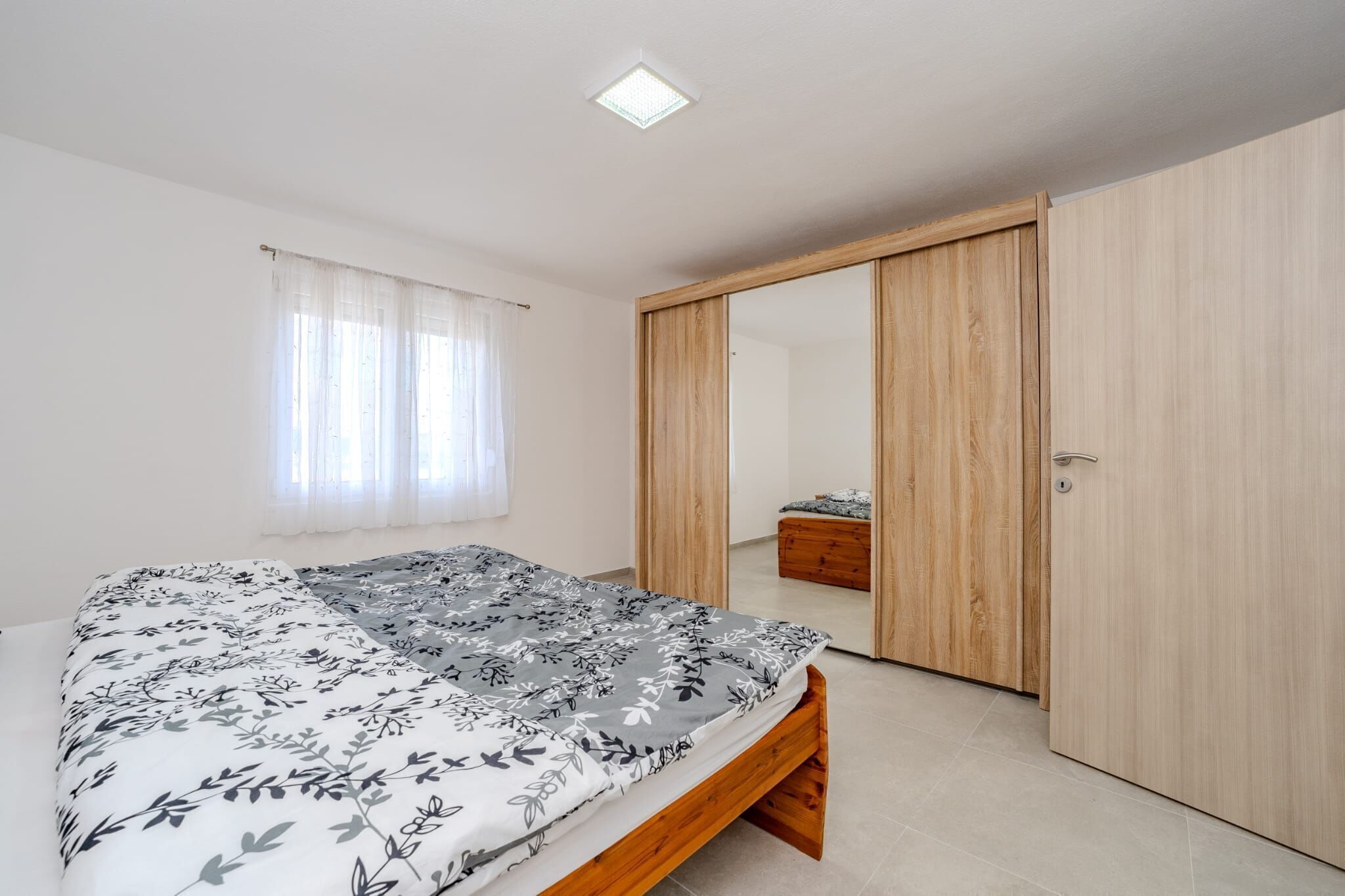 Een slaapkamer met een bed, een garderobe en een spiegel.