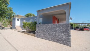 A modern two-story house with a stone facade, a covered porch, and a garage. - Apartments AS (Vodice)