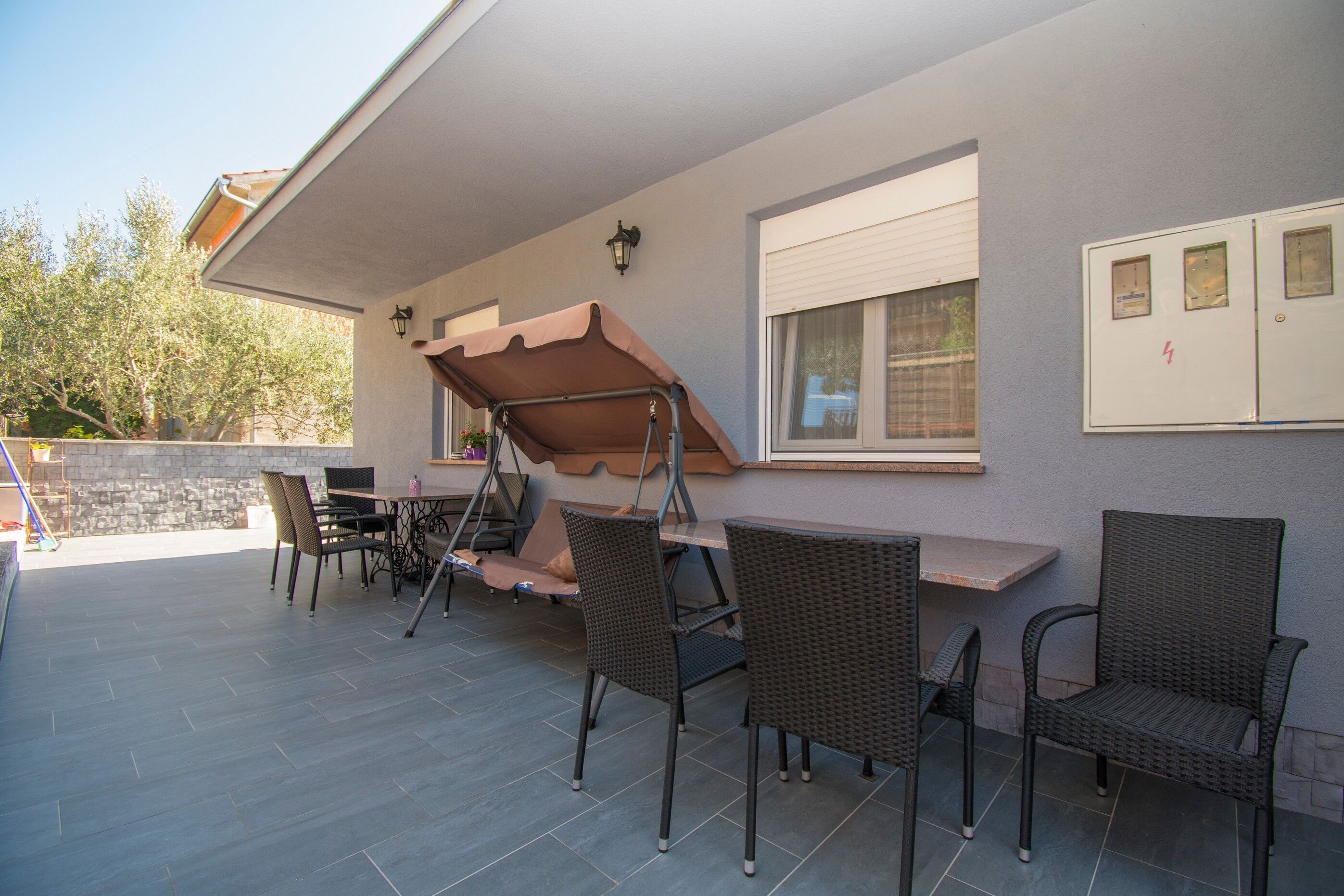 An outdoor patio area with a table and chairs, a swing, and a covered seating area.