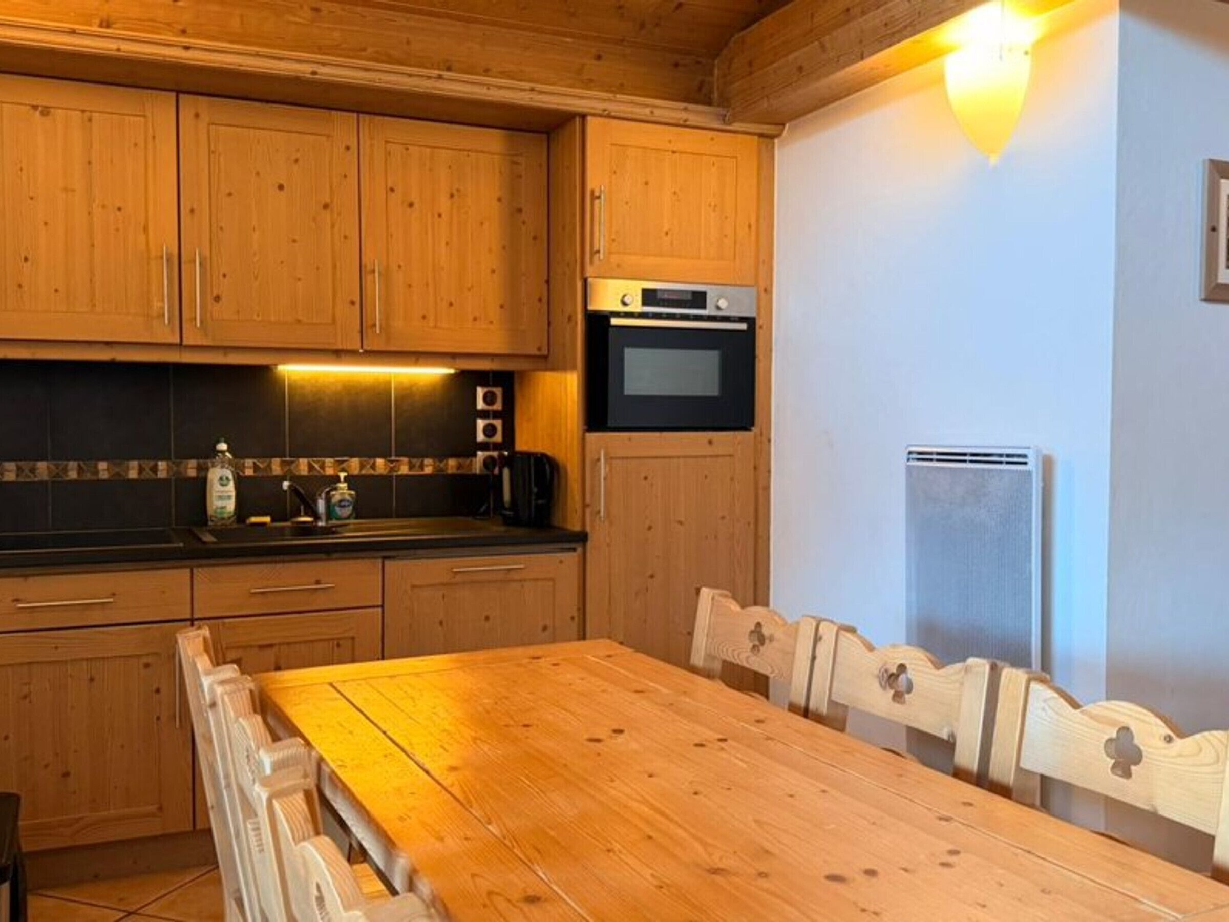 Eine Holzküche mit Schränken, einem Herd, einem Kühlschrank und einem Esstisch mit Stühlen.