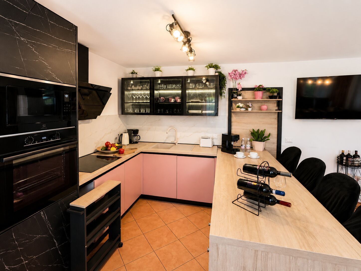 A modern kitchen with a black stove, a microwave, a sink, and a dining area with a wooden table and chairs.