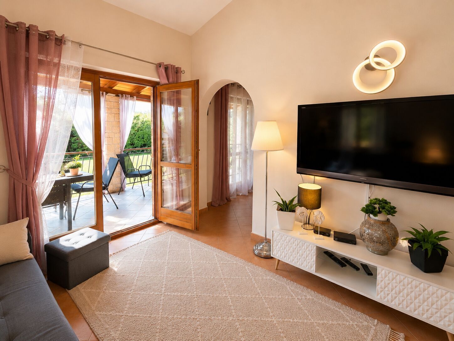 Uma sala de estar moderna com uma TV de tela plana, um sofá, uma mesa de centro e uma área de jantar com cadeiras e uma mesa.