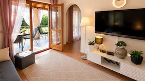 Een moderne woonkamer met een flatscreen televisie, een bank, een salontafel en een eethoek met stoelen en een tafel.