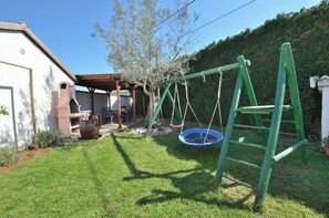 A backyard with a swing set, a small trampoline, and a barbecue area. - Villa Mia (Porec)