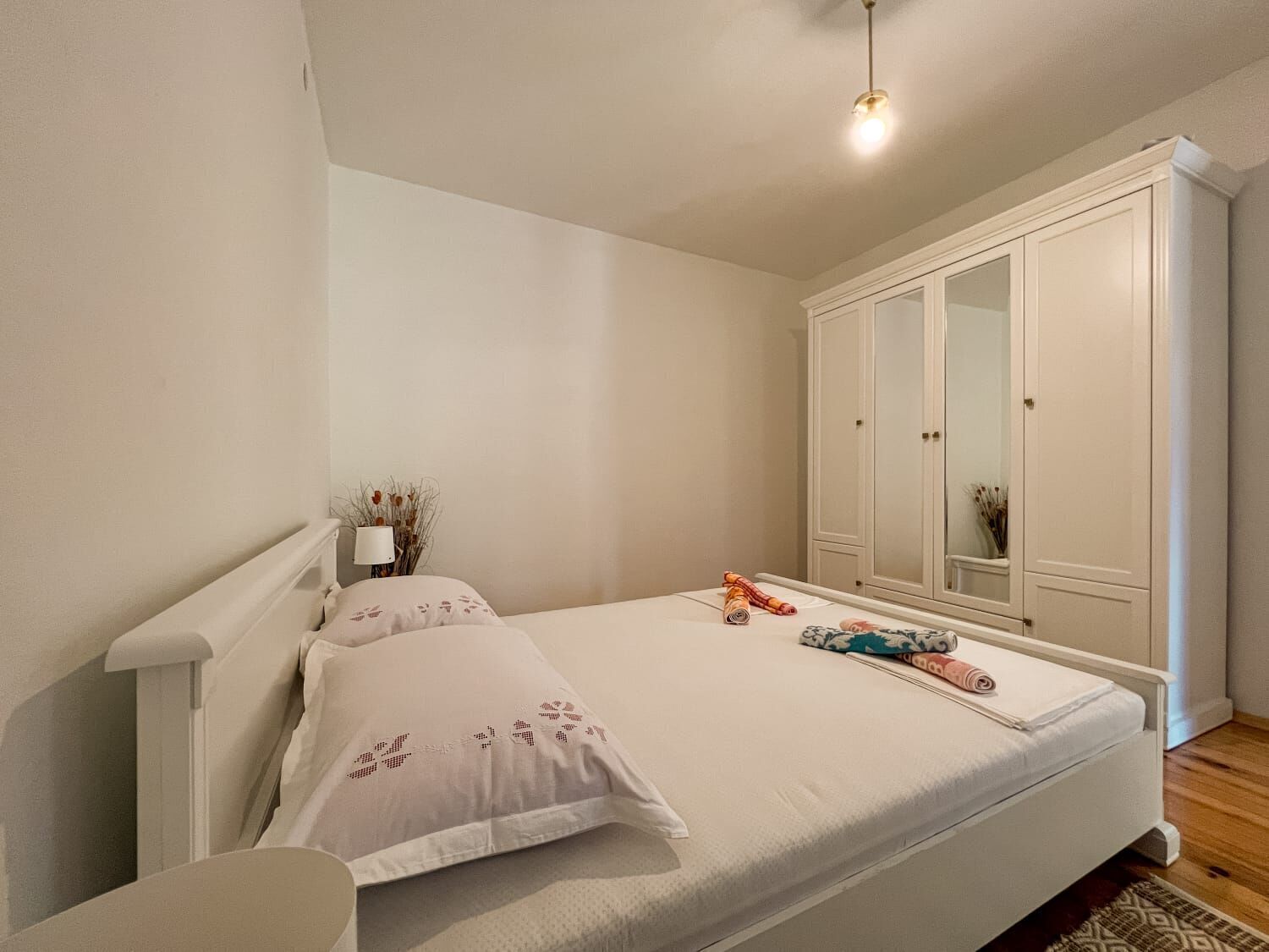 A bedroom with a bed, a wardrobe, and a bedside table.