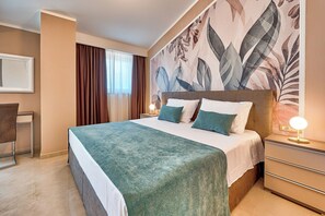 Ein Hotelzimmer mit einem großen Bett, einem Nachttisch mit Lampe, einem Sessel und einer Wand mit floralem Wandbild.