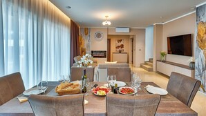 A dining area with a table set for four, a television, and a painting on the wall. - Villa Astrid (Rasa)