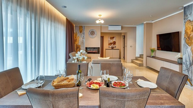 A dining area with a table set for four, a television, and a painting on the wall. - Villa Astrid (Rasa)