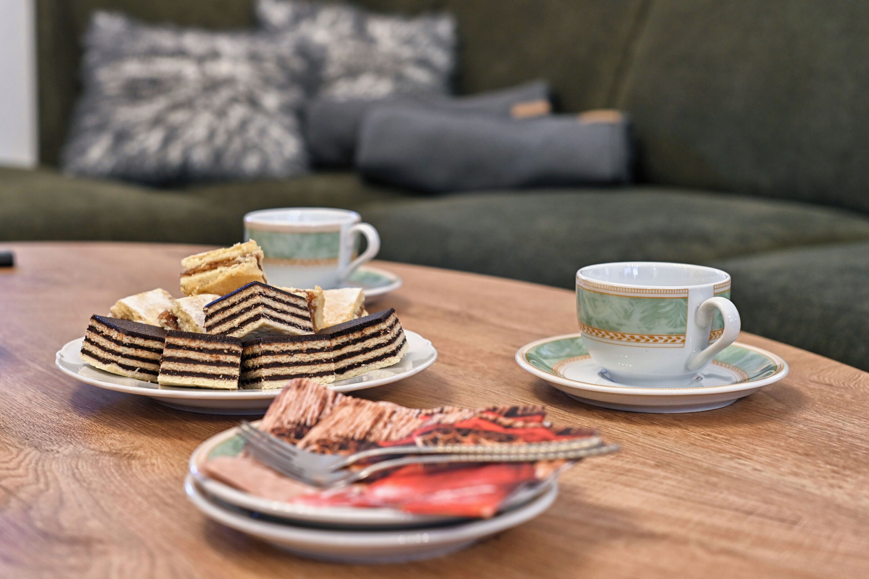 A table with a cake, a cup, and a plate with food items.