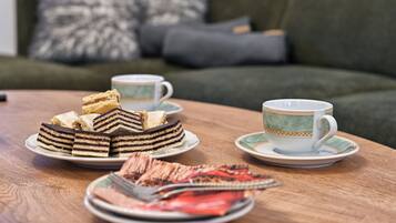 A table with a cake, a cup, and a plate with food items.