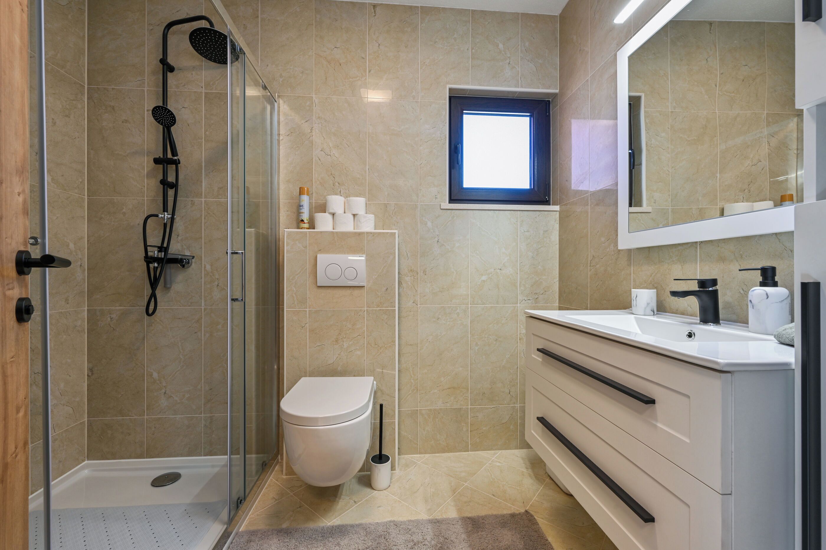 Une salle de bain moderne avec une douche à parois de verre, des toilettes et un meuble-lavabo avec un miroir.
