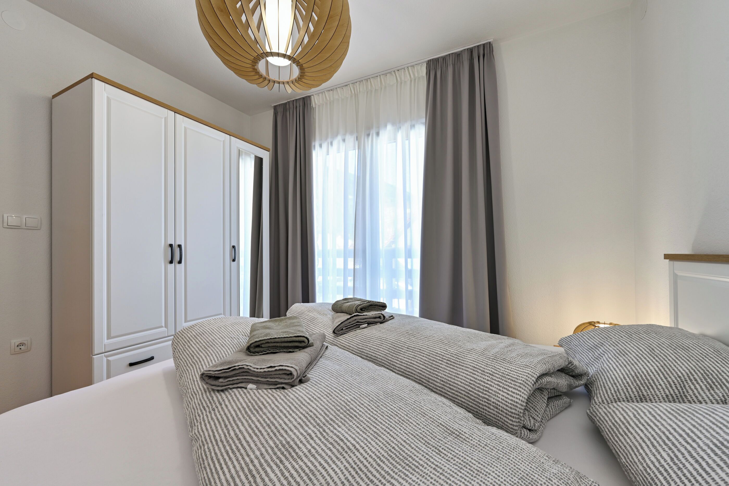 Una habitación de hotel con una cama grande, un armario y una ventana con cortinas.