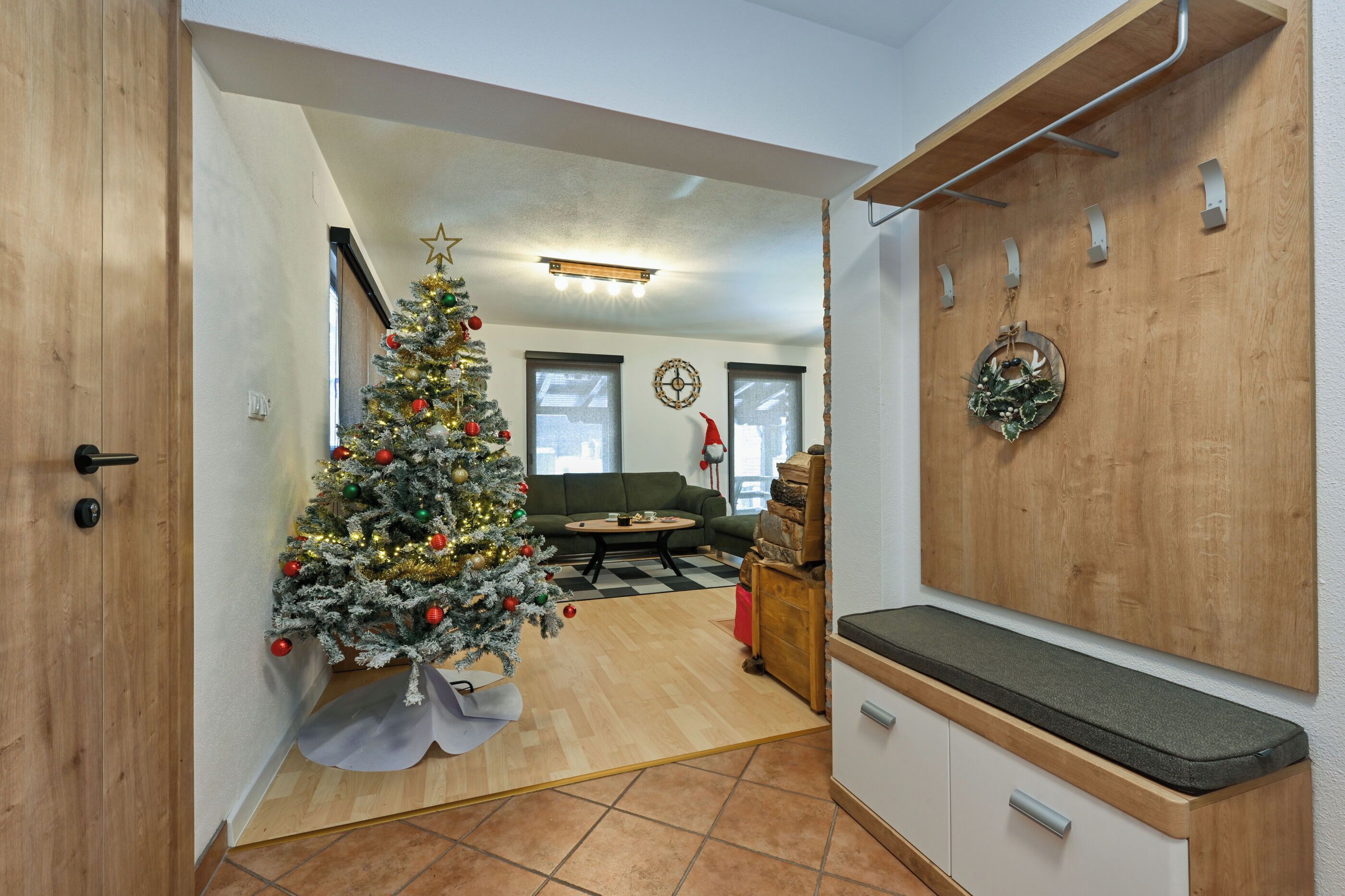 Un salon moderne avec un banc en bois, un petit sapin de Noël et un canapé.
