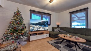 A modern living room with a Christmas tree, a flat-screen TV, a sofa, and a coffee table. - Apartments AVA (Ogulin)