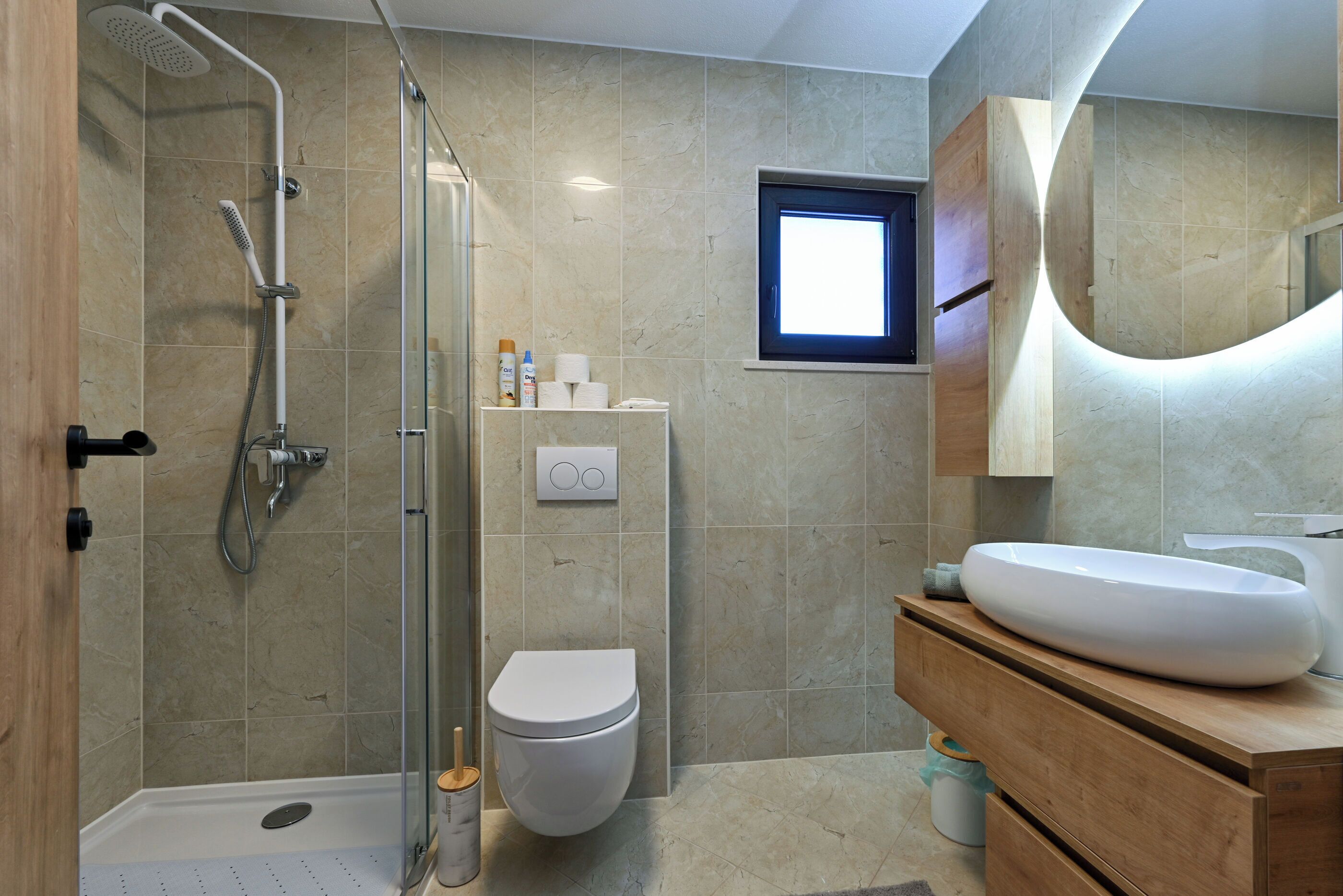 Une salle de bain moderne équipée d’une douche, de toilettes et d’un meuble-lavabo.