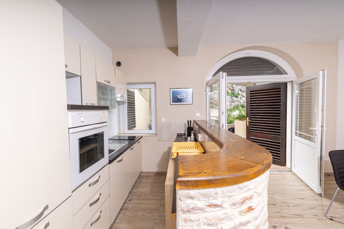 A modern kitchen with white cabinetry, a built-in oven, and a wooden island with a marble countertop.