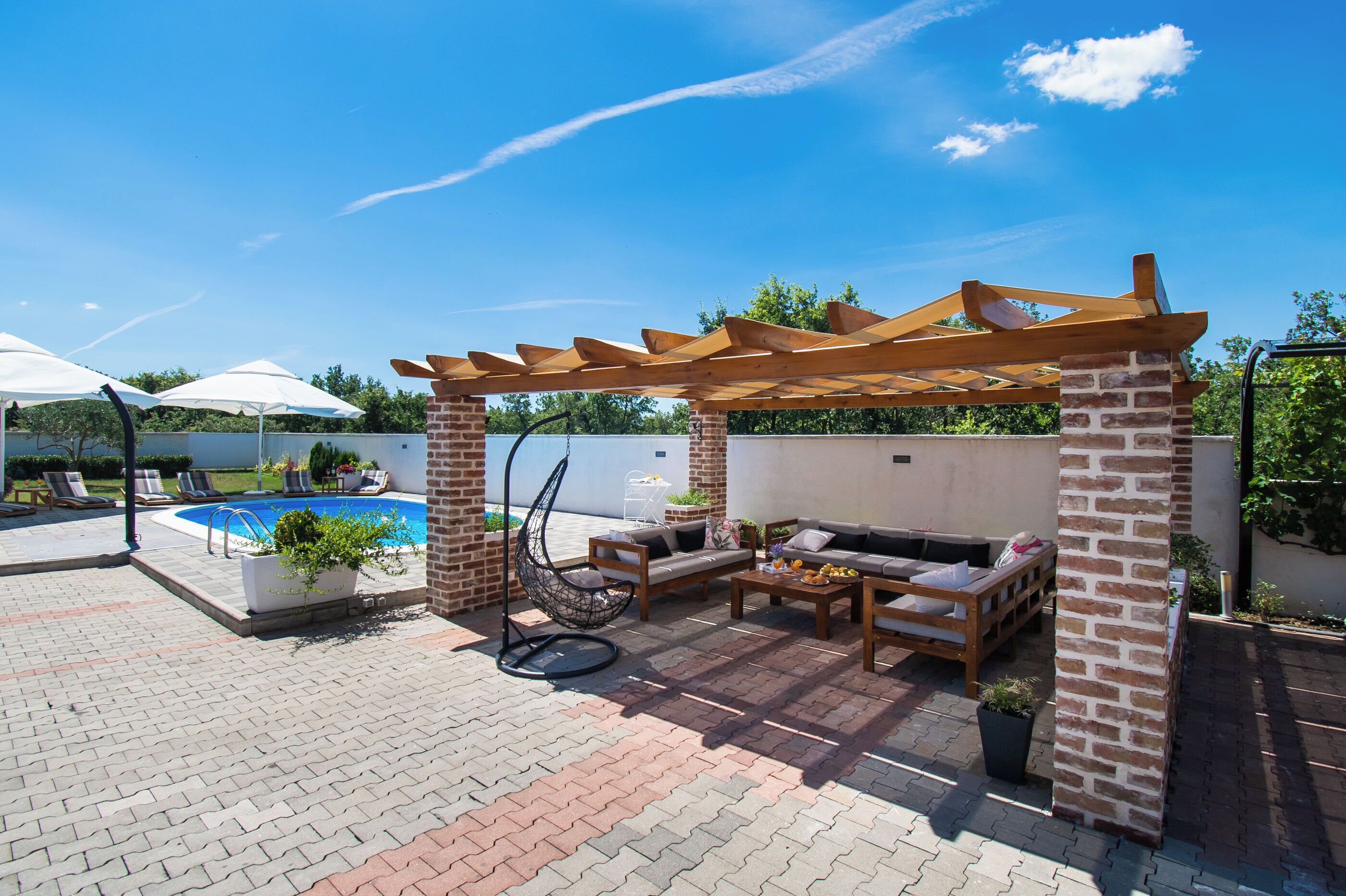 Un espace extérieur aménagé avec une piscine, des sièges et une pergola.