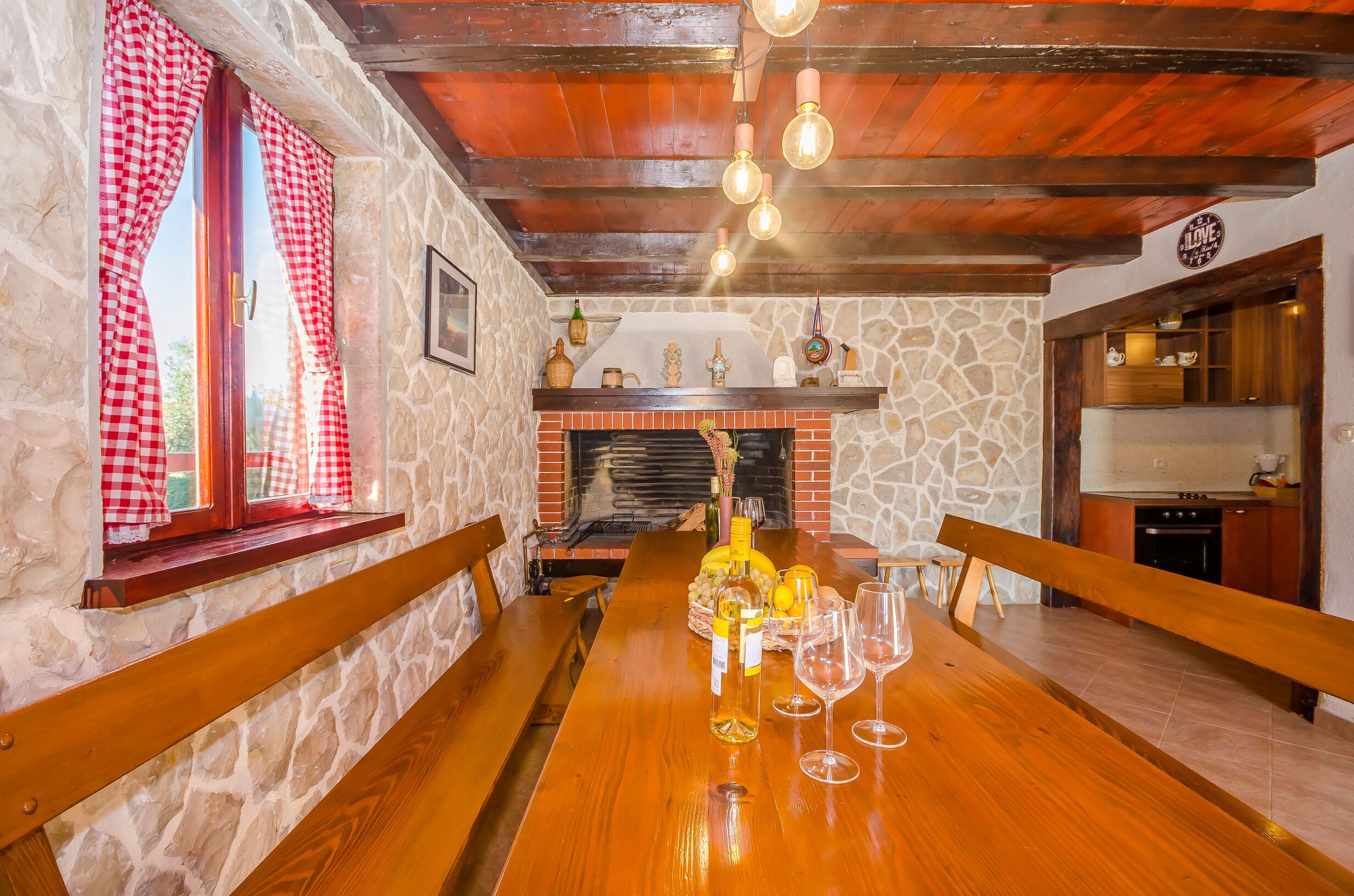 A dining area with a long wooden table, stone walls, and a fireplace.