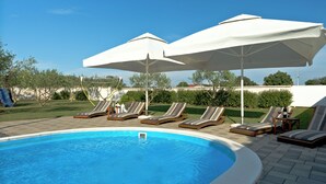En swimmingpool med liggestole og parasoller.