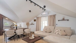 En moderne stue med sofa, stole, sofabord og spiseplads.