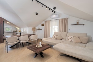 A modern living room with a sofa, chairs, a coffee table, and a dining area. - House Leonardo (Galovac)