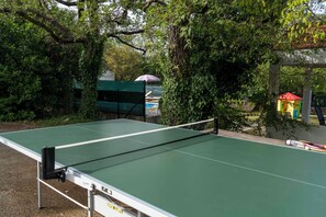 An outdoor table tennis table surrounded by trees and a small pavilion with a red roof. - House Edvard (Prgomet)
