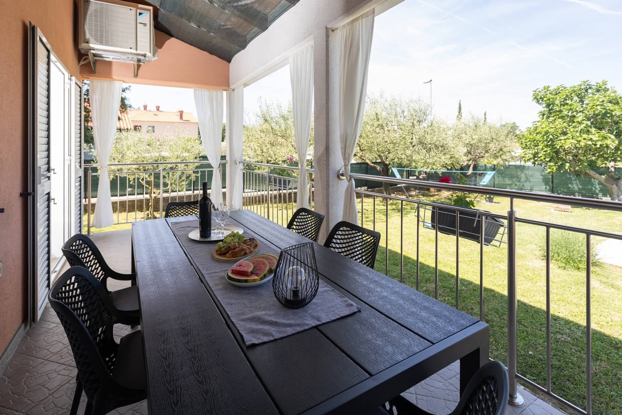 An outdoor dining area with a table set for two, a bottle of wine, and a candle.