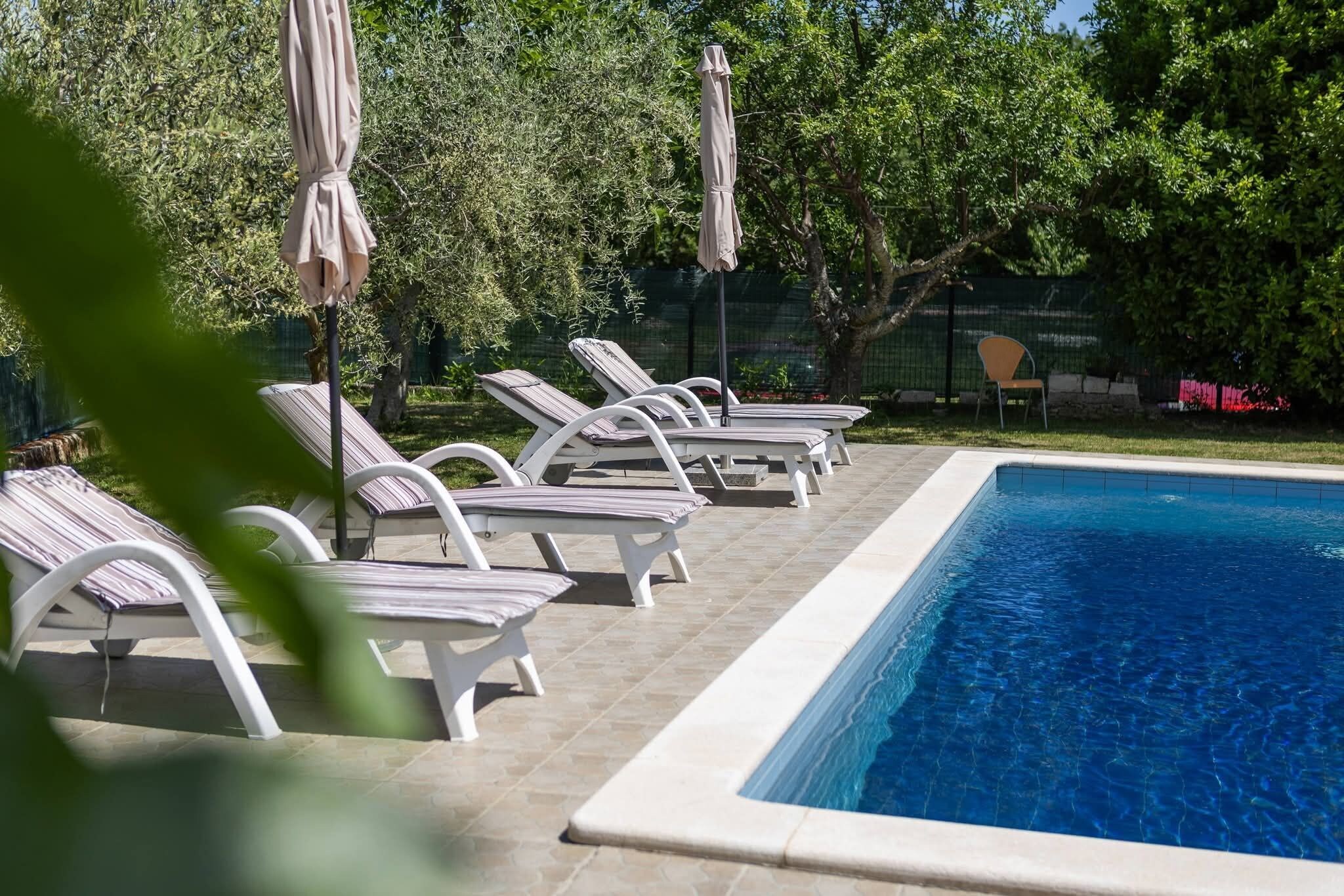 Una piscina con sillas de descanso y sombrillas.