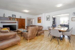 A modern living room with a flat-screen TV, a sofa, a coffee table, and a dining area with a table and chairs. - Villa Zelena Oaza (Labin)