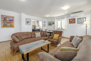 A modern living room with a brown sofa set, a wooden coffee table, and a dining area in the background. - Villa Zelena Oaza (Labin)