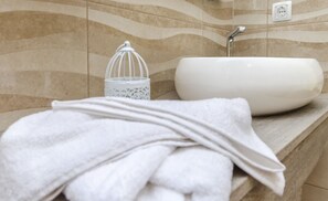 A bathroom with a white sink, a towel, and a decorative glass container. - Villa Galia (Tribunj)