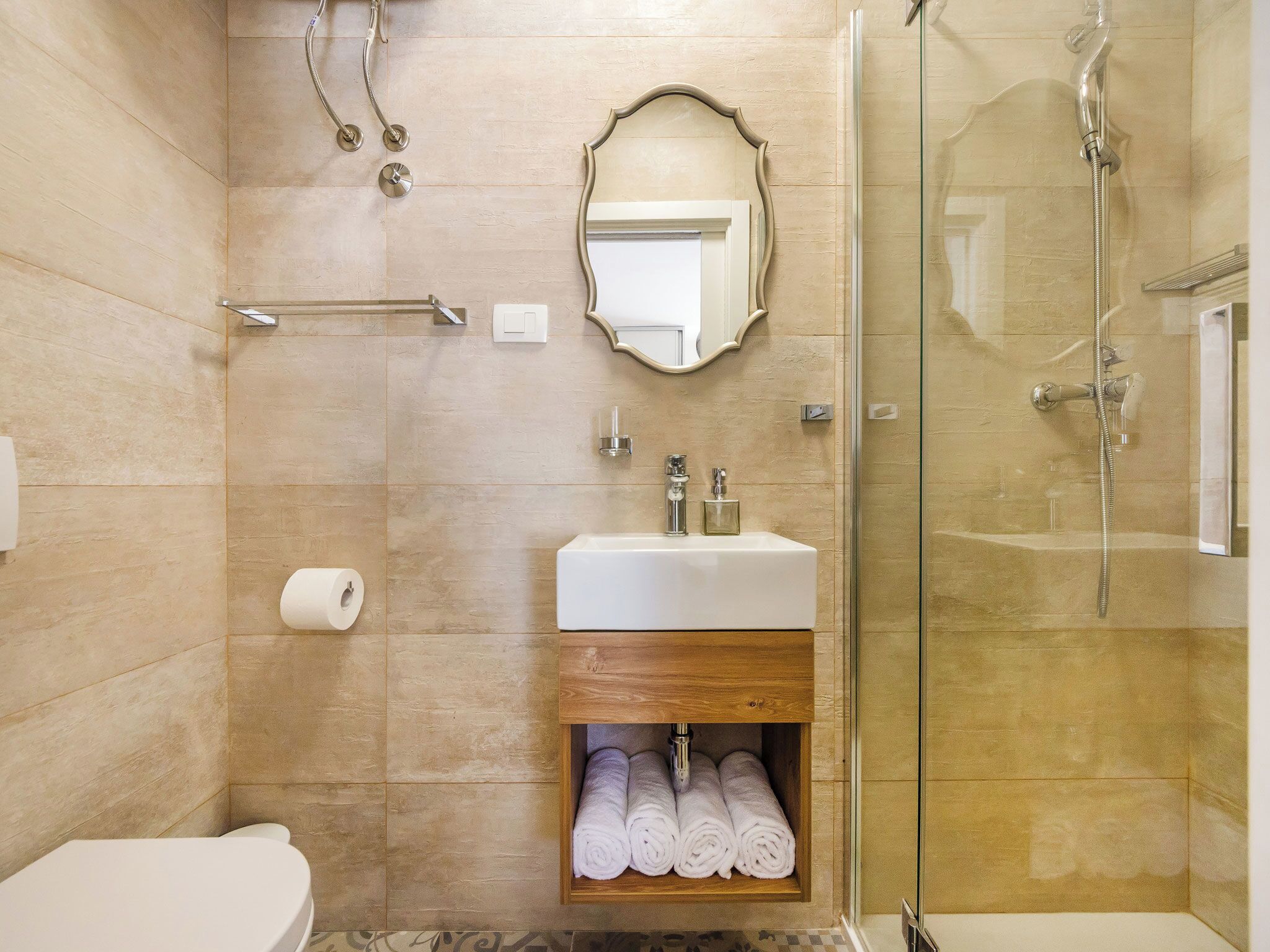 Een badkamer met toilet, wastafel met spiegel, douchecabine van glas en een handdoekhouder.