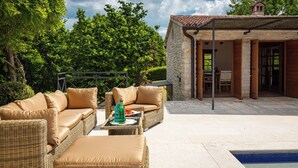 Eine Terrasse im Freien mit Korbmöbeln und einem Pool.