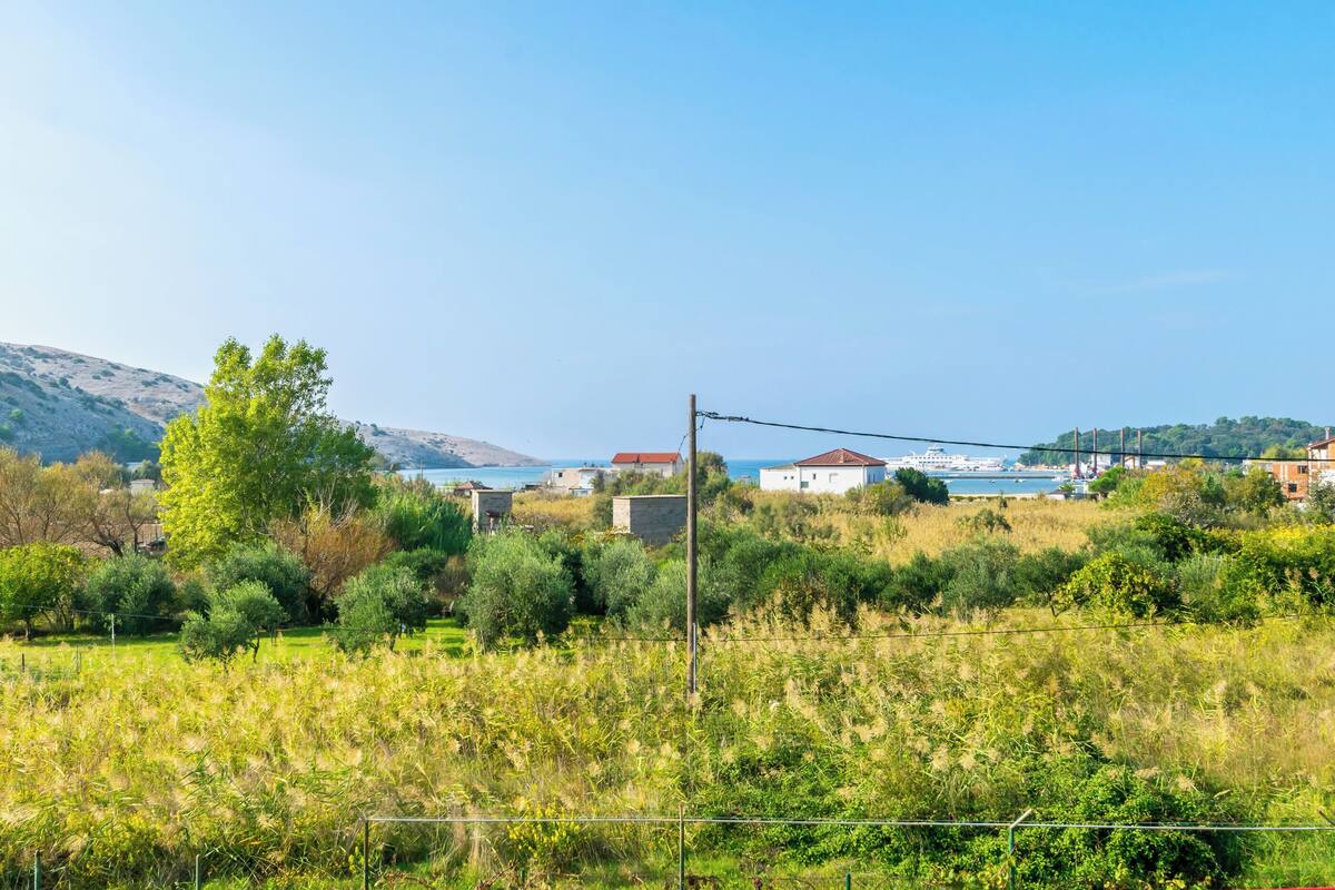 A coastal landscape with houses, a body of water, and a hilly backdrop.