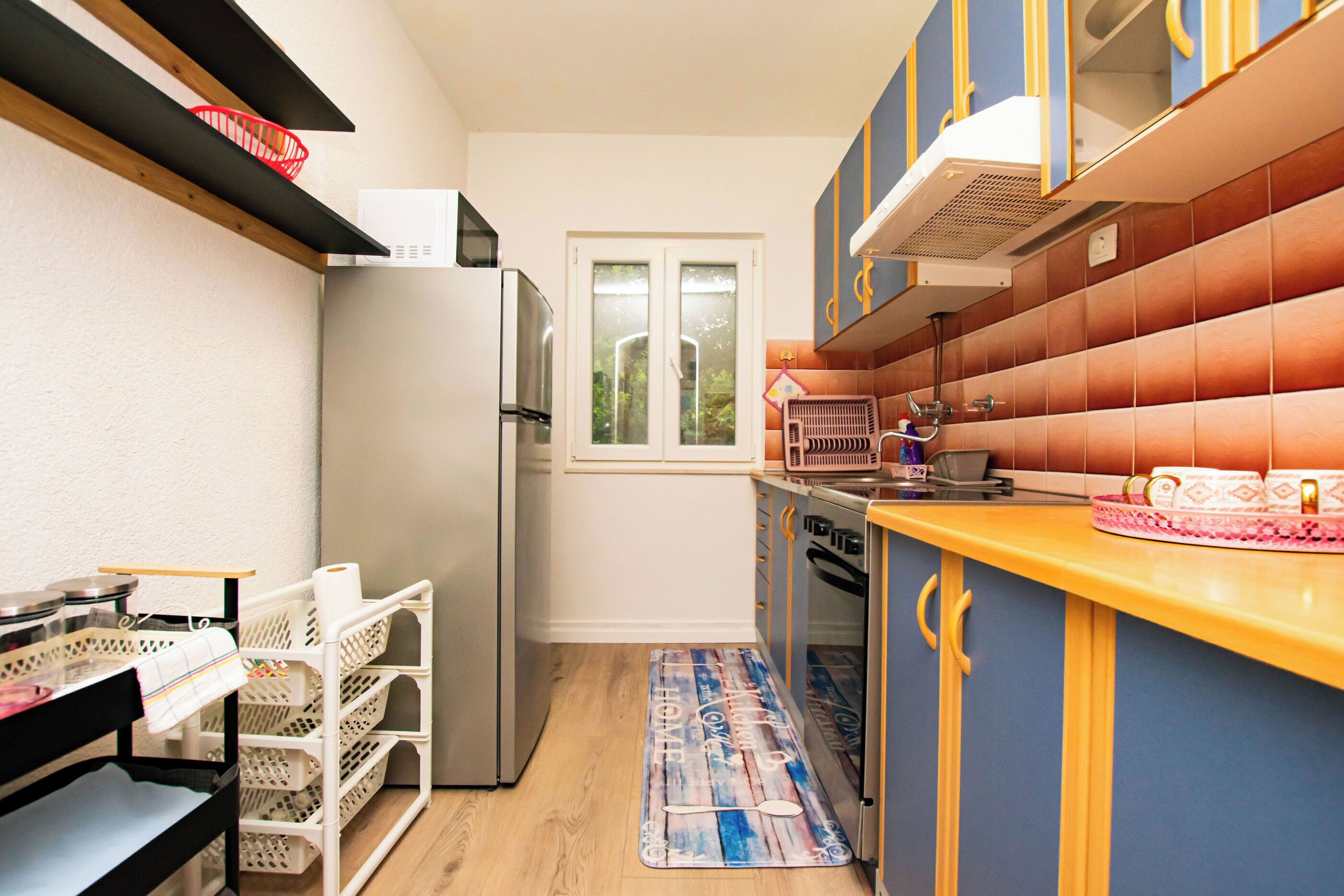 A compact kitchen with a refrigerator, stove, and cabinets.