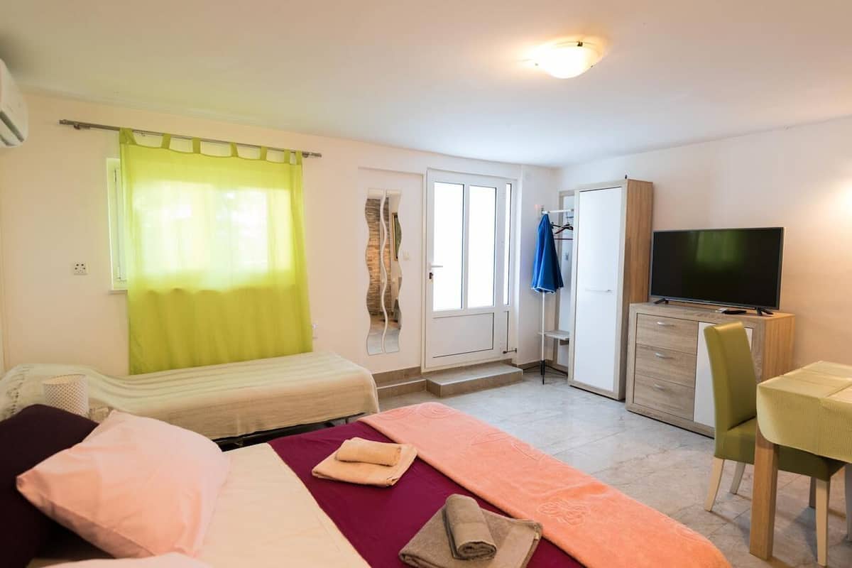 Ein Schlafzimmer mit einem Bett, einem Fernseher, einem Schreibtisch und einem Stuhl.