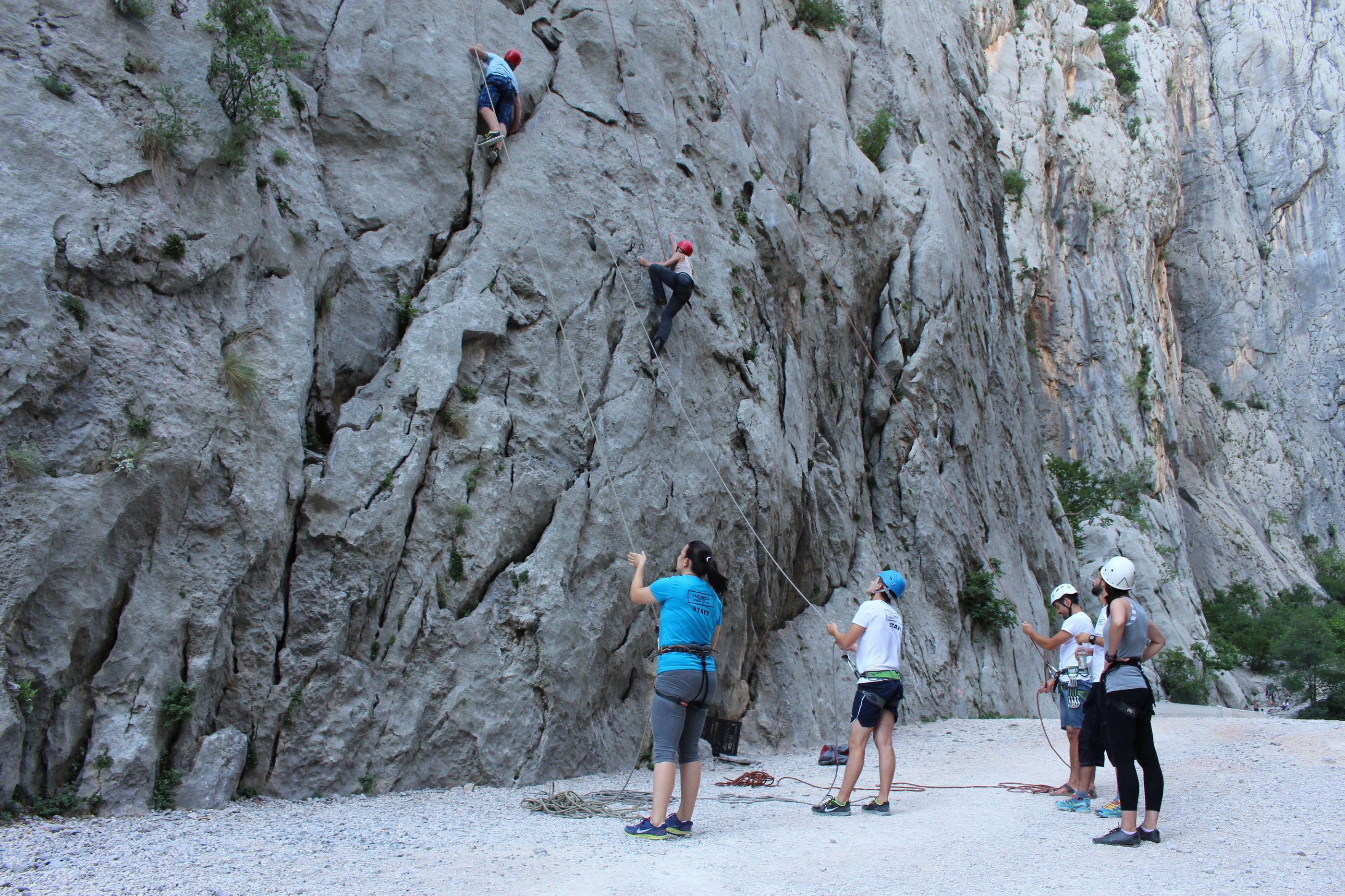 A group of people engaged in rock climbing on a steep, rocky cliff.