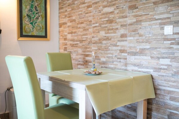 Un comedor con una mesa cubierta por un mantel texturizado, rodeada de sillas. Una botella decorativa y un pequeño plato están sobre la mesa.