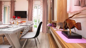 A dining area with a table set for two, a television mounted on the wall, and a decorative sculpture on a sideboard. - Apartments Baradic (Zadar)